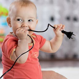 Un bébé avec une prise électrique dans la bouche