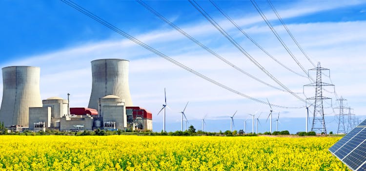Champ avec une centrale nucléaire et des infrastructures d'énergies renouvelables