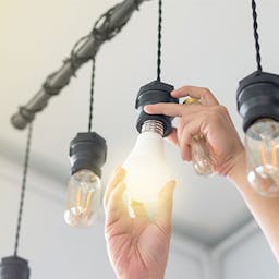 Un homme changeant une ampoule pour une ampoule basse consommation