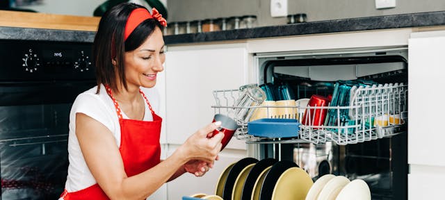 femme tablier rouge devant son lave vaisselle