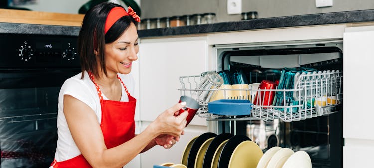 femme tablier rouge devant son lave vaisselle
