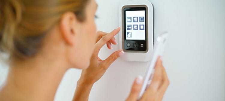 Une femme réglant son thermostat connecté