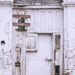 Une vieille porte abîmée avec un mur défraîchi