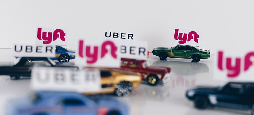 Petites voitures avec des pancartes Lyft ou Uber sur le capot.