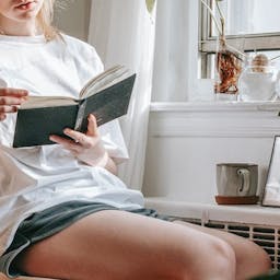 femme qui lit à côté d'un radiateur plantes vertes