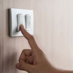 Une main appuyant sur interrupteur pour faire des économies d’électricité.
