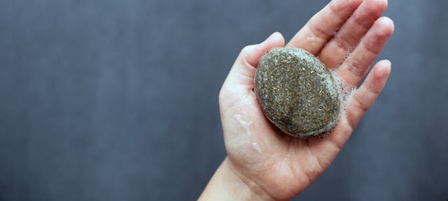 Un shampoing solide écologique savonnant dans une main