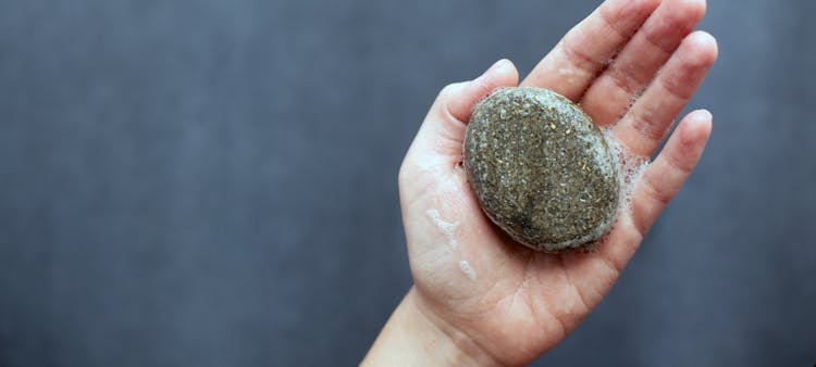 Un shampoing solide écologique savonnant dans une main