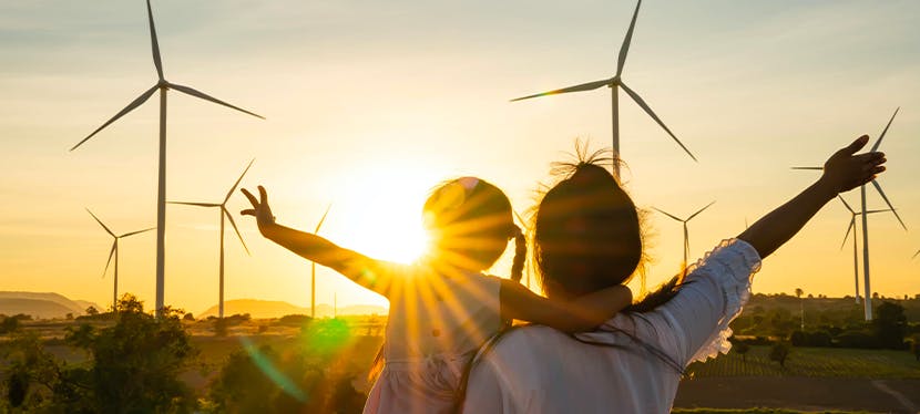 Une maman et sa fille font un signe de main aux éoliennes