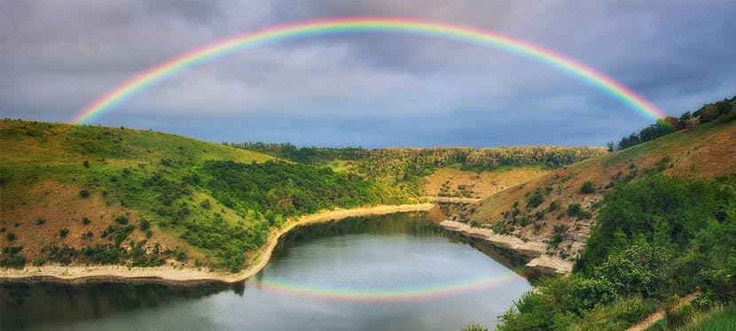 Arc-en-ciel sur un lac entouré de de collines