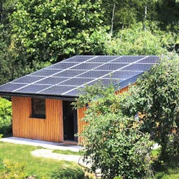 Petite maison aux toits de panneaux solaire dans un espace vert