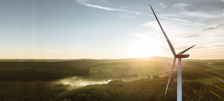 Une éolienne qui tourne avec une vallée verte en contrebas