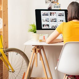 Une étudiante, dans son appartement assise à son bureau en train de travailler