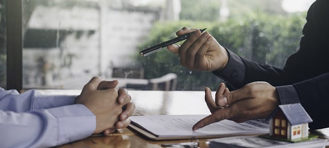 Une personne montrant un contrat et tendant un stylo à une autre personne