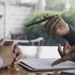 Une personne montrant un contrat et tendant un stylo à une autre personne