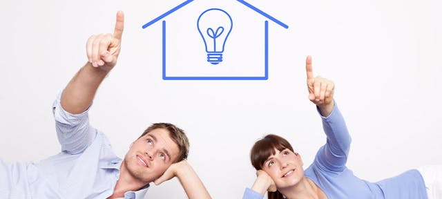 Un homme et une femme pointant du doigt une maison avec une ampoule au milieu
