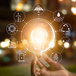 La production d'énergie représentée par une ampoule tenue dans une main et différents pictogrammes des moyens de production 