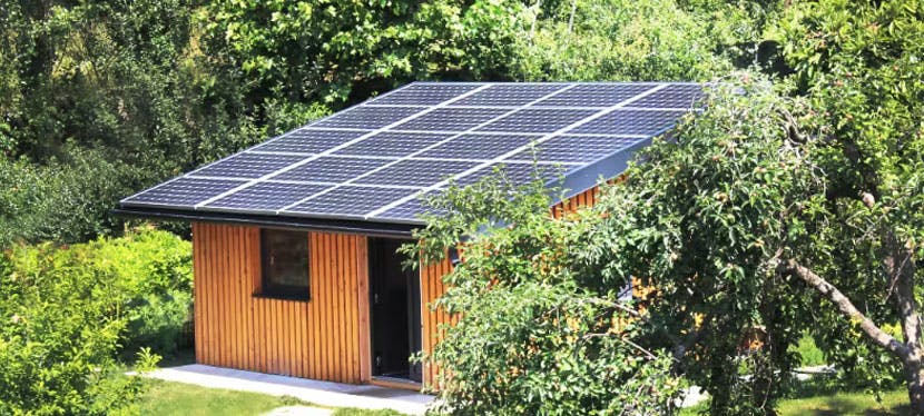 Petite maison aux toits de panneaux solaire dans un espace vert