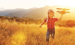 Enfant courant dans les champs avec un avion à la main