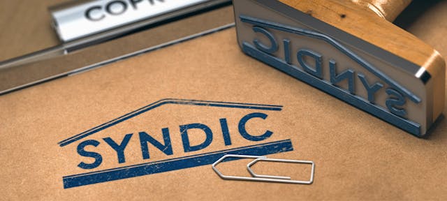Tampon d'encre avec inscrit "syndic" sur un dossier de copropriété