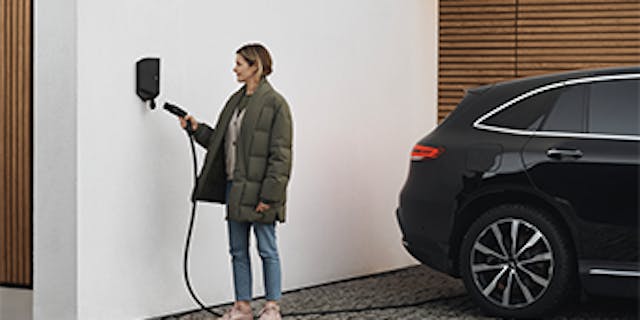 Une femme en train de brancher sa voiture électrique à une borne de recharge