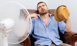 Un homme écrasé de chaleur assis à côté de son ventilateur
