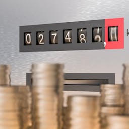 Une pile de pièces devant un compteur de kWh qui défile : le TRV de l'électricité, également appelé le tarif bleu.