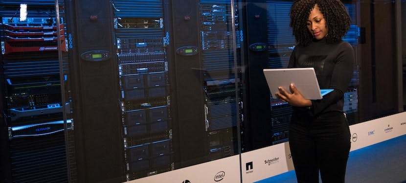 femme devant un data center avec un ordinateur dans les mains