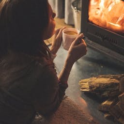 Femme buvant du café devant un poêle