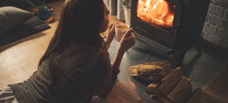 Femme buvant du café devant un poêle