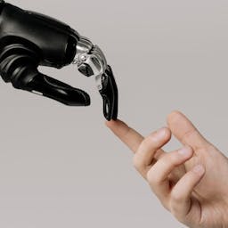 une main d'humain qui touche un doit de robot
