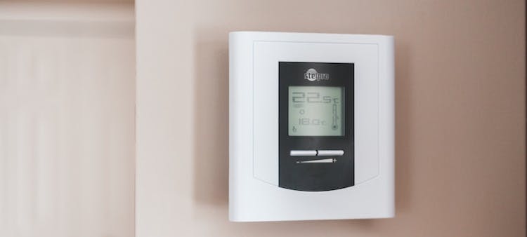 Thermostat connecté posé sur un mur beige