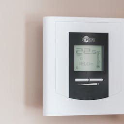 Thermostat connecté posé sur un mur beige