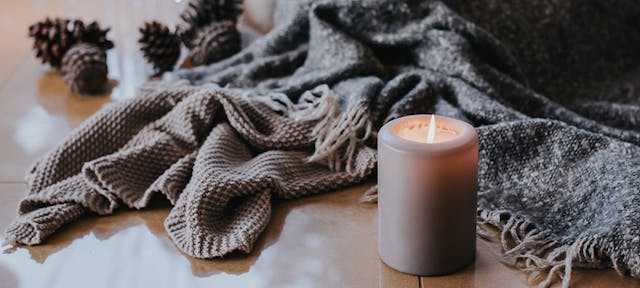 Un plaid et une bougie sur le parquet d'une maison