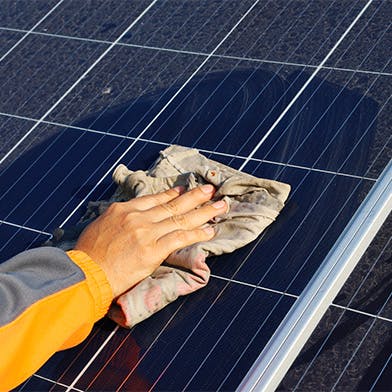 Une personne nettoyant un panneau solaire avec un chiffon humide : l'entretien d'un panneau solaire
