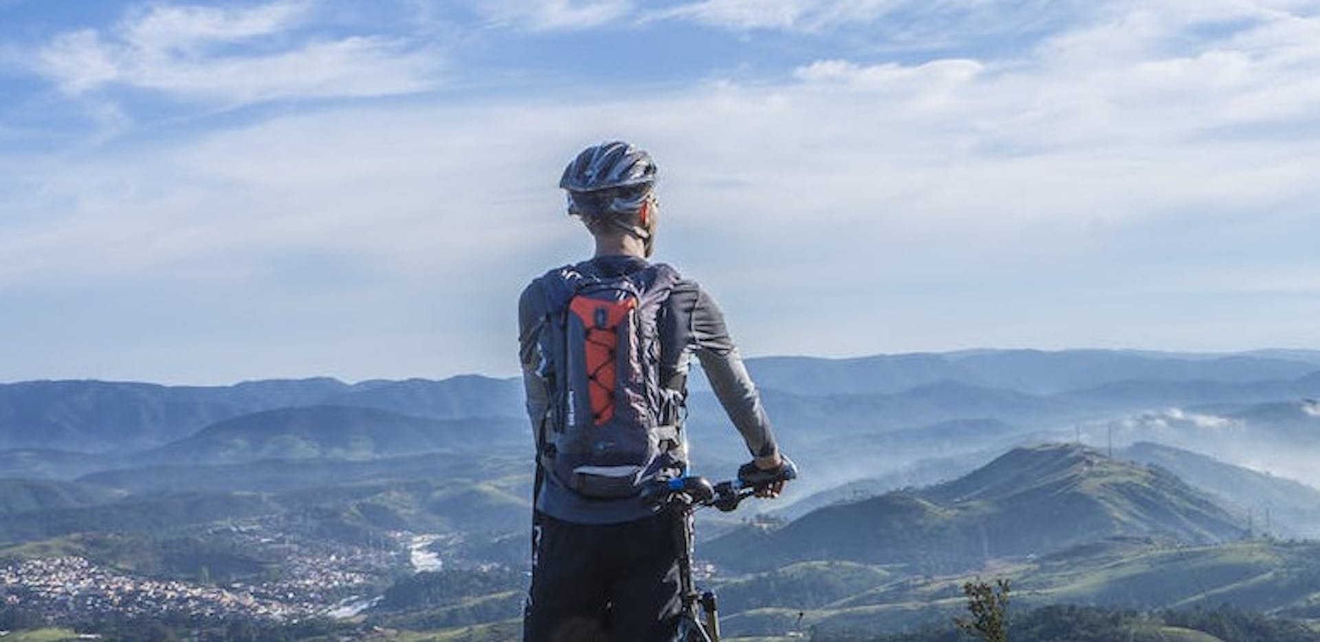 Un homme tenant son vélo éléctrique et regardant le paysage.
