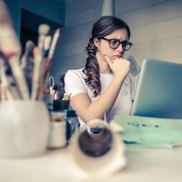 Une femme interrogative devant un ordinateur