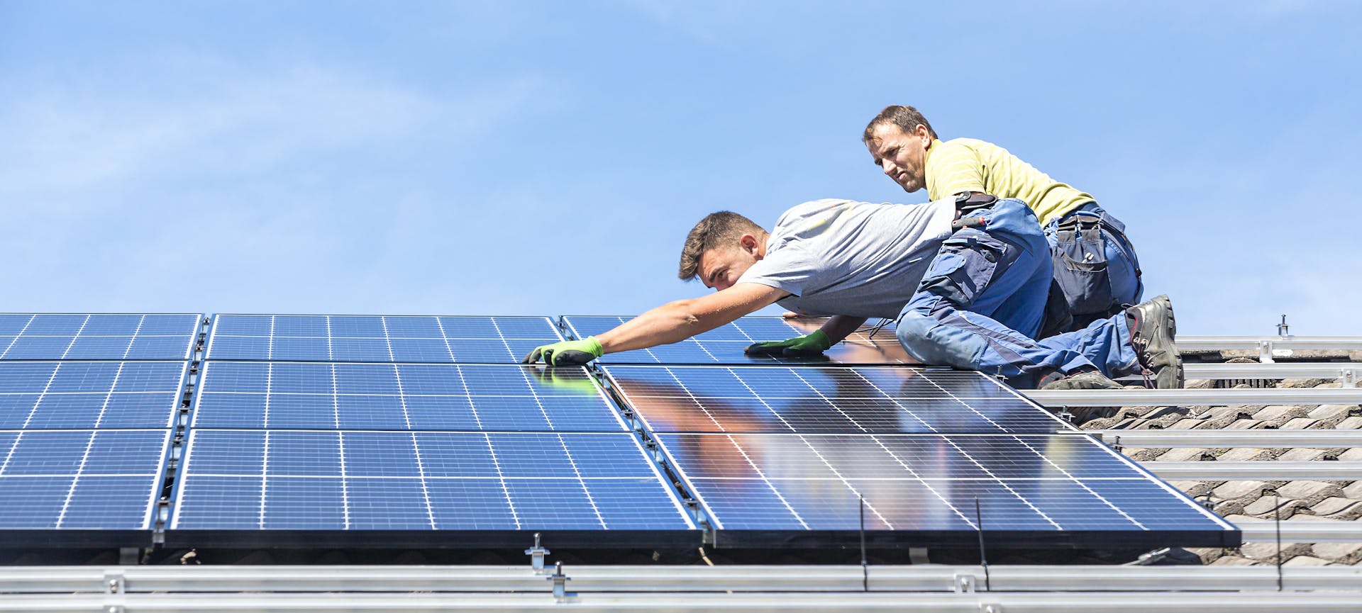 Autoconsommation, deux personnes installent des panneaux solaires sur un toit