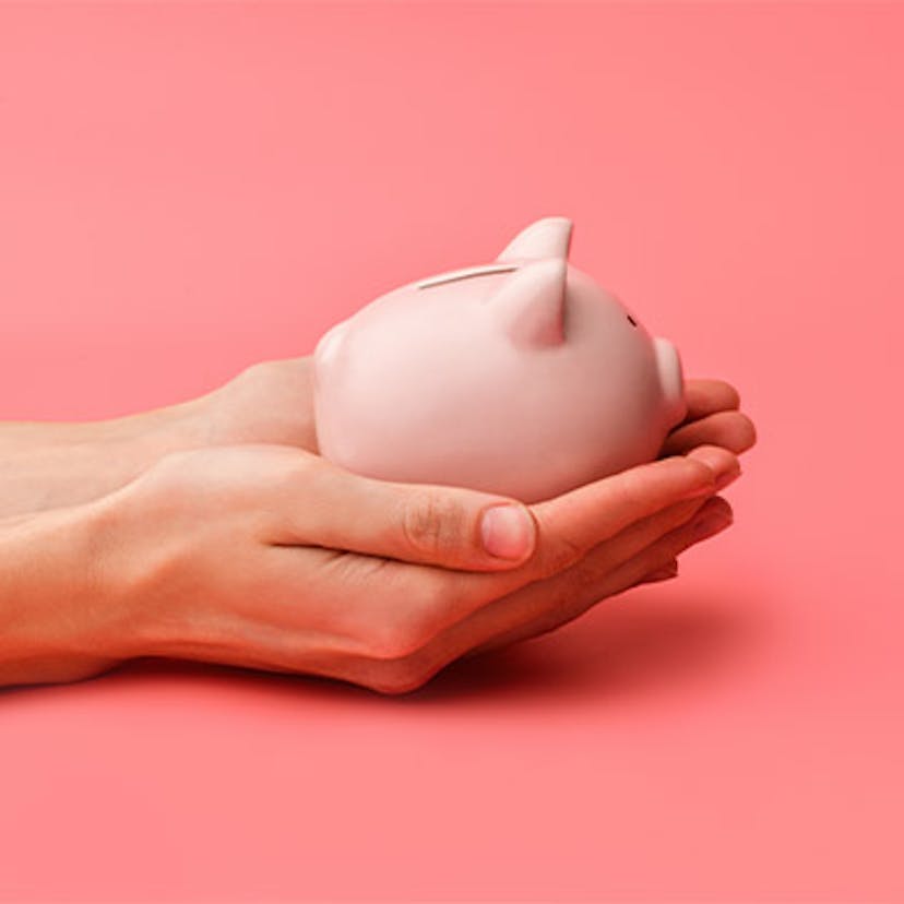 Deux mains qui tiennent une petite tirelire en forme de cochon rose qui représente l'autoconsommation avec la vente de surplus