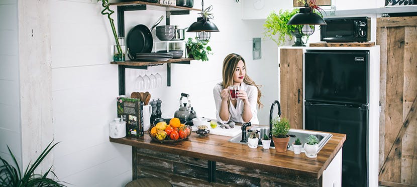 Femme dans une cuisine, sirotant un thé rouge