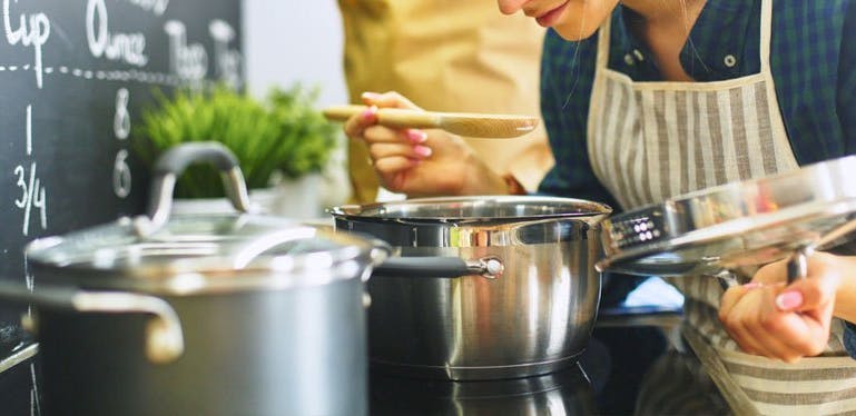 Une femme en train de cuisiner, penchée au-dessus d'une marmite.