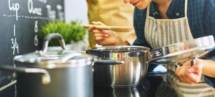 Une femme en train de cuisiner, penchée au-dessus d'une marmite.