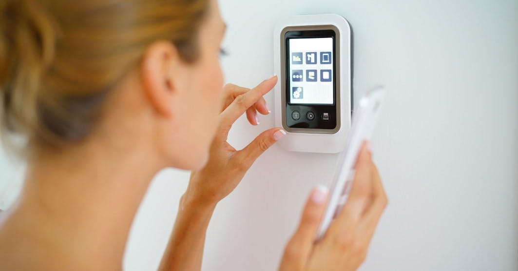 Une femme réglant son thermostat connecté