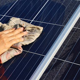 Une personne nettoyant un panneau solaire avec un chiffon humide : l'entretien d'un panneau solaire
