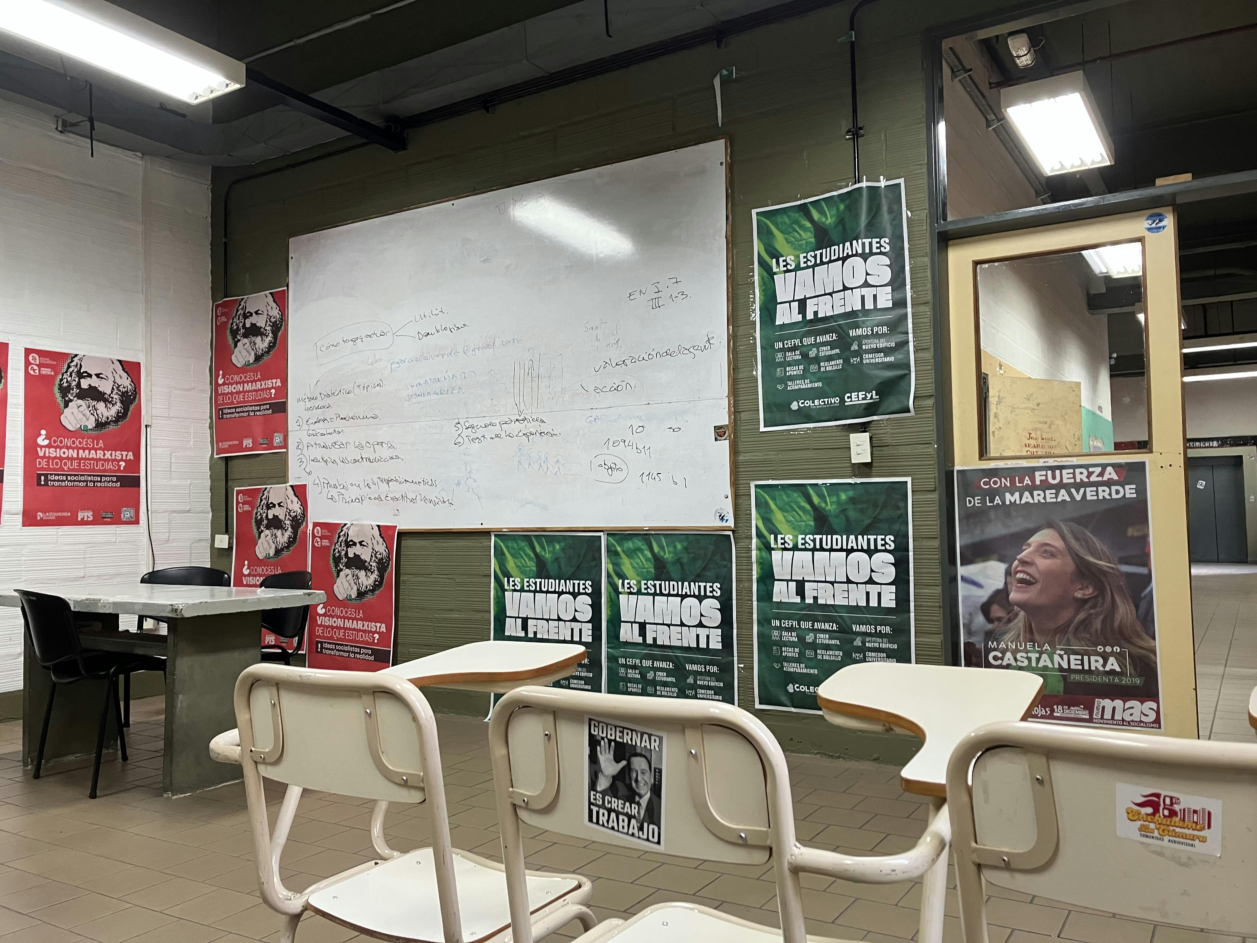 This is not the classroom shared in the description. One poster reads, "To govern is to create jobs," and another reads, "Are you familiar with the Marxist vision of your studies?"