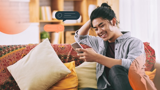 A student looking at his phone and smiling. Text bubble graphics surround him.