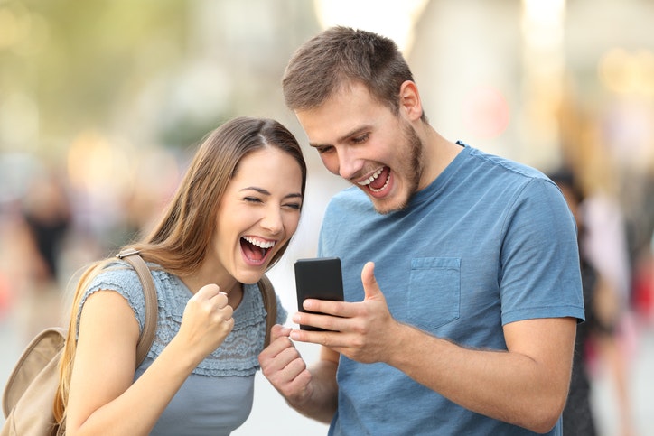 Excited couple receiving a direct admissions acceptance from a college or university on line outside stock photo