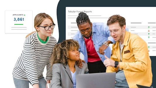 A group of students and staff gathered around a computer. Images of analytics screens and figures behind them.