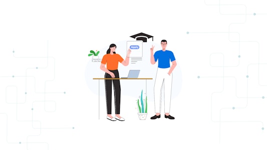 Two students standing in front of a laptop filling out a college application.