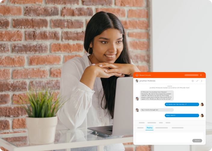Female student happy at her computer. She is chatting with a staff member at Element University